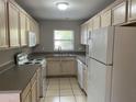 Bright kitchen features a double basin sink, window, white appliances, and light wood cabinets at 3112 E 8Th Ave, Tampa, FL 33605