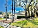 Exterior side view of home showcasing the two-car garage and mature trees for shade at 3358 Tanglewood Trl, Palm Harbor, FL 34685
