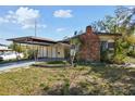 Front exterior of a single-story home with carport, brick chimney, and well-lit front yard at 4002 W Gray St, Tampa, FL 33609