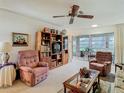 Cozy living room featuring plush armchairs, a ceiling fan, and a sliding glass door to the screened patio at 4955 Grist Mill Cir, New Port Richey, FL 34655