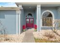 Charming entrance with a red double-door, complemented by elegant arched windows and vibrant potted plants at 5140 Eclipse Ct, Spring Hill, FL 34607