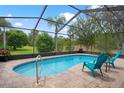 Enclosed pool with brick patio, outdoor furniture, and view of a lush yard, perfect for relaxation at 5140 Eclipse Ct, Spring Hill, FL 34607