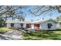 Quaint single-story house featuring a white tile roof, boat trailer and an outdoor garage with a red door at 120 Carlyle Cir, Palm Harbor, FL 34683