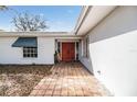 Exterior view of front entrance with red doors and tile walkway leading up to the home at 120 Carlyle Cir, Palm Harbor, FL 34683