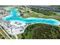 Spectacular aerial view of the community lagoon, showcasing the sandy beach, turquoise water, and surrounding homes at 9119 Forge Breeze Loop, Wesley Chapel, FL 33545