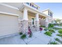 Charming home featuring a welcoming front porch with stone accents and well-manicured landscaping at 9119 Forge Breeze Loop, Wesley Chapel, FL 33545
