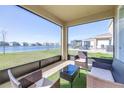 Relaxing screened patio overlooking a serene lake, furnished with cozy wicker seating for outdoor enjoyment at 9119 Forge Breeze Loop, Wesley Chapel, FL 33545