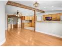 Open-concept living space with wood floors, exposed beams, and a view of the kitchen with wood cabinetry at 19531 Deer Lake Rd, Lutz, FL 33548
