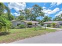 A single-story home with light-blue paint, stone accents, a fenced yard, mature trees and is located on a paved street at 2412 Giddens Ave, Seffner, FL 33584