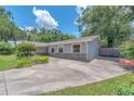 A single-story home features a spacious driveway, stone accents, light-blue paint, manicured landscaping, and flowering plants at 2412 Giddens Ave, Seffner, FL 33584