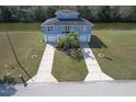 Aerial view of blue home near canal, with a well manicured lawn and double driveway at 4010 Jewfish Dr, Hernando Beach, FL 34607