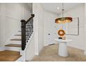 Bright foyer with hardwood stairs, iron railing, pendant lighting, and round table decor at 12785 Jade Empress Loop # 202, Venice, FL 34293