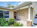 Charming front porch features a decorative metal art piece, a brick pillar, and verdant landscaping at 2873 Doone Cir, Palm Harbor, FL 34684