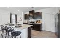 Modern kitchen featuring dark cabinets, stainless steel appliances, and a spacious island with bar seating at 5230 Salt Marsh Rd, Wimauma, FL 33598
