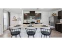 Bright kitchen with dark cabinets, stainless steel appliances, and an island with bar seating at 5230 Salt Marsh Rd, Wimauma, FL 33598