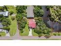 An aerial view of a red-roofed home nestled in a lush, tree-filled landscape, close to a tranquil waterfront area at 9501 Alice Ln, Riverview, FL 33578