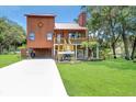 Charming two-story stilt home with wood siding, a metal roof, and a spacious front yard at 9501 Alice Ln, Riverview, FL 33578