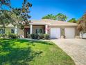 Charming single-story home with a manicured lawn and a three-car garage offers inviting curb appeal at 12010 Hardaman Pl, Tampa, FL 33618