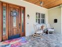 Inviting front porch featuring a stained wood ceiling, rocking chairs, and a decorative glass front door at 12010 Hardaman Pl, Tampa, FL 33618