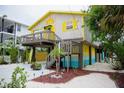 Side view of colorful beach house featuring a sun deck and tropical landscaping at 2504 Avenue B # A, Bradenton Beach, FL 34217
