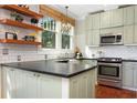 Well-lit kitchen with stainless steel appliances, dark countertops, and open shelving with hanging chandelier at 3000 4Th N Ave, St Petersburg, FL 33713