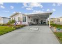 Charming single-story home features a well-manicured lawn, carport, and vibrant landscaping with colorful flowers at 37545 Lilly Bea Ave, Zephyrhills, FL 33541