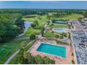 This aerial view showcases community pools, tennis courts and a scenic golf course surrounded by mature trees at 3829 Trophy Blvd, New Port Richey, FL 34655