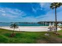 Scenic beach view with white sand, palm trees, blue water, and a bridge in the distance at 5900 Bahia Del Mar Cir # 137, St Petersburg, FL 33715