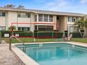 Community pool with fencing and a lounge area, adjacent to a well-maintained building with green trim at 8303 Bardmoor Blvd # 105, Seminole, FL 33777