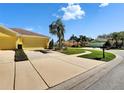 Charming yellow house featuring a well-manicured lawn and a spacious driveway under a sunny, blue sky at 11539 Captiva Kay Dr, Riverview, FL 33569