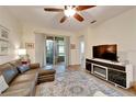 Bright living room featuring a leather sectional, ceiling fan, and sliding glass door to the patio at 11539 Captiva Kay Dr, Riverview, FL 33569
