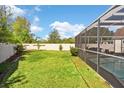 Spacious backyard features a well-maintained lawn, partial fencing, and a screened-in pool area for relaxation at 13411 Beechberry Dr, Riverview, FL 33579