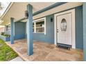 Inviting front porch with stone flooring, modern lighting fixtures, and a decorative front door with an oval window at 1466 Laconia W Dr, Clearwater, FL 33764