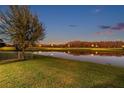 Scenic backyard view with lush green lawn and a tranquil pond reflecting the twilight sky at 4522 Tramanto Ln, Wesley Chapel, FL 33543