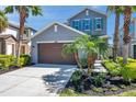 Well-maintained two-story home with blue shutters, a two-car garage, and beautiful landscaping with palm trees at 4522 Tramanto Ln, Wesley Chapel, FL 33543