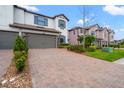 Contemporary townhouse with a brick driveway, two-car garage, and lush landscaping at 4896 San Martino Dr, Wesley Chapel, FL 33543