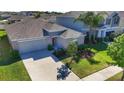 Birds eye view of single Gathering residence highlighting mature trees, landscaping, a spacious driveway and gray roof at 10115 Paradise Fish Dr, Riverview, FL 33578