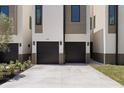 Beautiful modern home exterior showcasing a two-car garage and lush landscaping around a long driveway at 222 N Hesperides St, Tampa, FL 33609