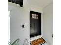 Stylish black front door with glass panel, welcome mat, and modern exterior lighting creating a charming and inviting entrance at 4118 Ramona Dr, Spring Hill, FL 34606