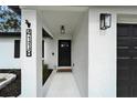 Charming home entrance with black door, stylish exterior lighting, house numbers and 'Let it Snow' door mat at 4118 Ramona Dr, Spring Hill, FL 34606