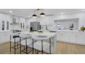 Modern kitchen featuring white cabinetry, stainless steel appliances, quartz countertops, and a large center island at 5426 Creeping Hammock Dr, Sarasota, FL 34231