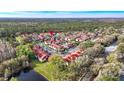 Overhead view of the residential community boasting red-roofed condos nestled amongst green trees and a serene lake at 9481 Highland Oak Dr # 1410, Tampa, FL 33647