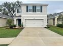 Inviting two-story home boasts a two-car garage and well-maintained lawn with vibrant floral accents at 10908 Carlton Fields Dr, Riverview, FL 33579