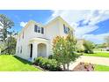 Charming two-story home with neutral stucco, dark shutters, arched entry, and mature landscaping at 10908 Carlton Fields Dr, Riverview, FL 33579