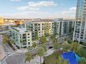 Wide aerial view of condo with balconies, palm trees, street-level shops, blue sky, and water in the background at 111 N 12Th St # 1819, Tampa, FL 33602