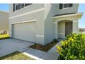 Close-up of a two-story home's garage and front entrance with a landscaped yard at 30910 Penny Surf Loop, Wesley Chapel, FL 33545