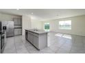 Spacious kitchen featuring a large island, stainless steel appliances, and tiled floors at 30910 Penny Surf Loop, Wesley Chapel, FL 33545
