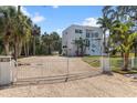View of the property featuring an imposing white exterior gate and a gravel driveway at 375 Wellington Ave, Oldsmar, FL 34677