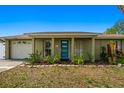 Inviting single-story home featuring a brick facade and a striking blue front door at 1012 Greenleaf Way, Tarpon Springs, FL 34689