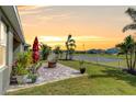 Spacious backyard with a brick patio, fire pit, lush lawn, white fence, and tropical landscaping, ideal for outdoor living at 11605 Cleyera Ct, Riverview, FL 33579